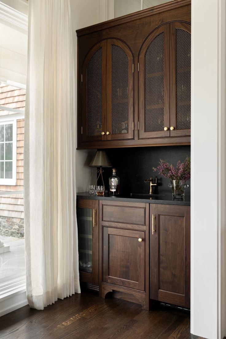 a kitchen with wooden cabinets and white curtains