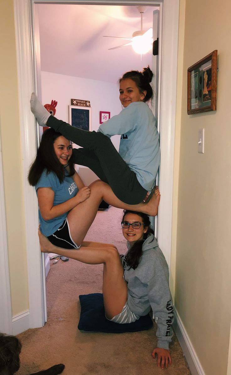 three girls are hanging upside down on the floor in front of an open door and one girl is smiling at the camera