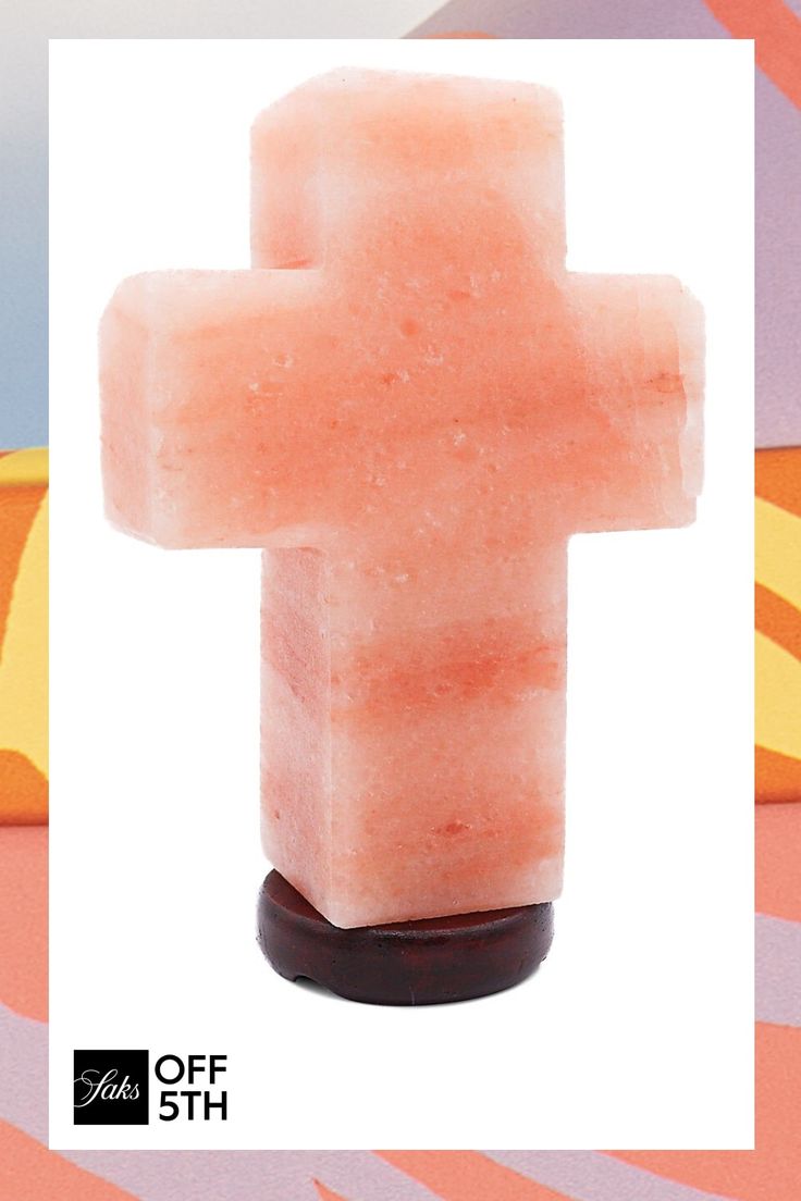 a cross made out of soap sitting on top of a wooden stand in front of a colorful background