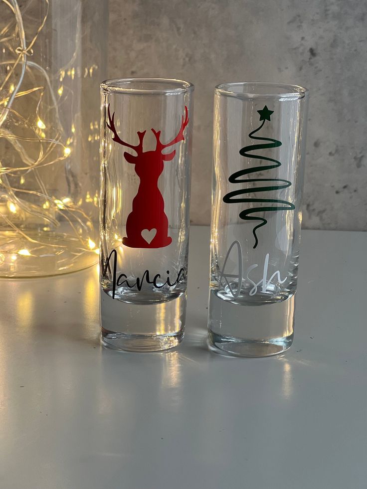 two glasses sitting on top of a white table next to a christmas tree with lights in the background