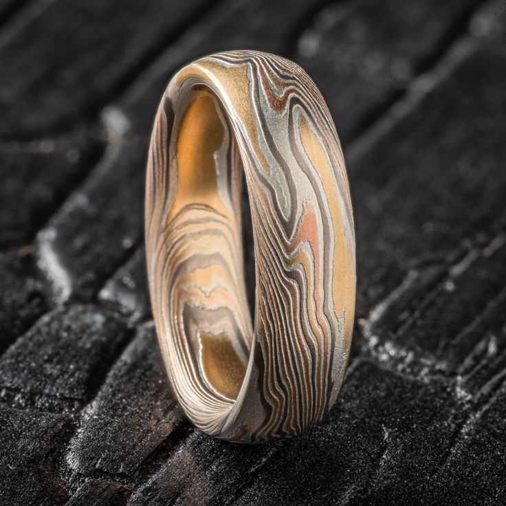 "* Price may vary depending on ring size, please inquire with us directly with your needed size for accurate pricing! This bold and beautiful Mokume Gane ring features our Twist pattern and non oxidized Firestorm metal combination with an etched finish, and low dome profile. The Firestorm palette features 14k yellow gold, 14k red gold, palladium and sterling silver.  Mokume Gane Band Pattern: Twist Palette: Firestorm Width Shown: 5mm Size Shown: 5.5 Finish: Etched  Profile: Low Dome Price does NOT include stones or setting fees. We care about customer service and would like to hear from you! Please contact us to help create your treasured item, we take your concerns and requests to heart and will work together to create your unique designs SPECIAL PRICING FOR SETS. CONTACT US WITH YOUR DES Unique Carved Rings For Wedding, Adjustable Carved Rings For Anniversary, Carved Adjustable Jewelry For Wedding, Mokume Gane Ring Wedding, Mokume Gane Ring, Twist Pattern, Mokume Gane, Pattern Ring, Ring Ideas