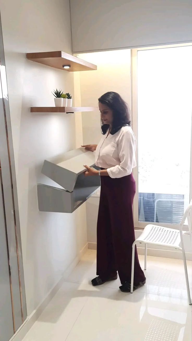 a woman standing next to a wall holding a box