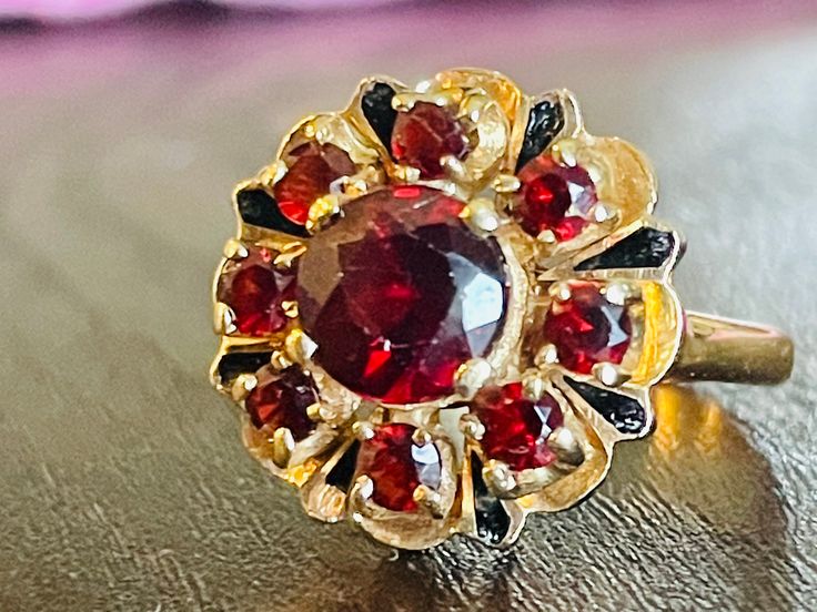 Beautiful stately antique Genuine round cut Bohemian Garnet ring set in 14k gold. There is a round cut center stone garnet measuring 6.1mm diameter and 4.1mm deep equating to 1.36 carats. The surrounding 8 round cut garnets are 2.5mm diameter for another 0.065 carats each. Total Bohemian Garnet Carat weight for this ring is nice 2.1 Carats! In between each smaller round Garnets, there are enamel painted pear shapes that are a very nice accent touch to this ring. Bohemian Garnets are amongst the Antique Yellow Gold Round Ruby Ring, Victorian Hallmarked Cluster Ring, Vintage Garnet Ring With Center Stone, Round Multi-stone Ruby Ring With Garnet, Victorian Multi-stone Ruby Ring, Victorian 14k Gold Cluster Ring With Gemstone, Victorian Cluster Ring With Center Stone, Antique Multi-stone Ruby Ring, Victorian Style Ruby Ring For Anniversary