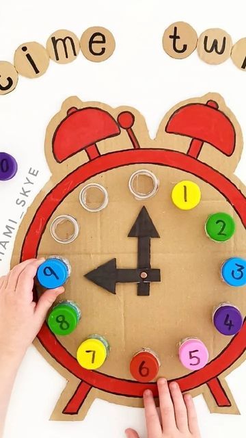 a child's hand is on top of a clock made out of construction paper