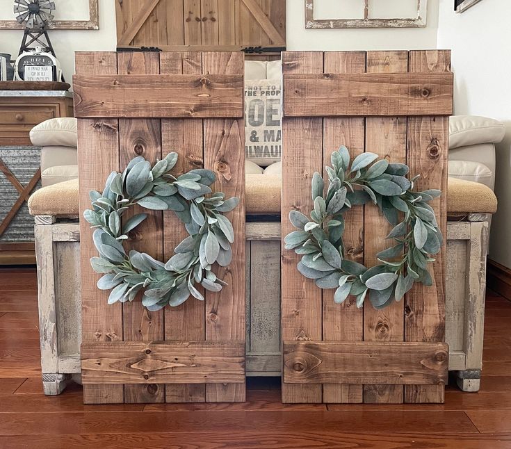 two wooden doors with wreaths on them in front of a white couch and chair