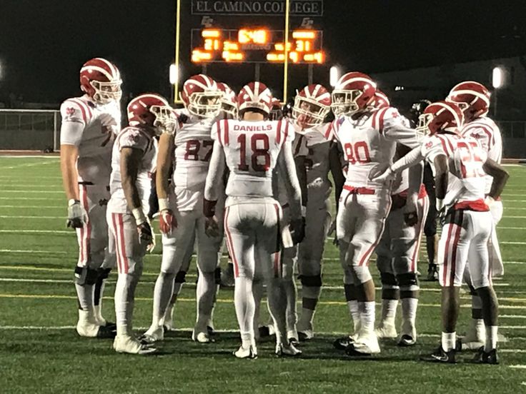 the football team is standing in a huddle on the sidelines at night time