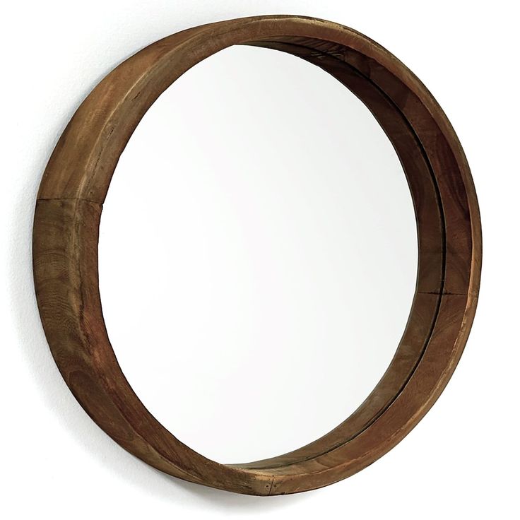 a circular mirror hanging on the wall next to a white wall with a wooden frame