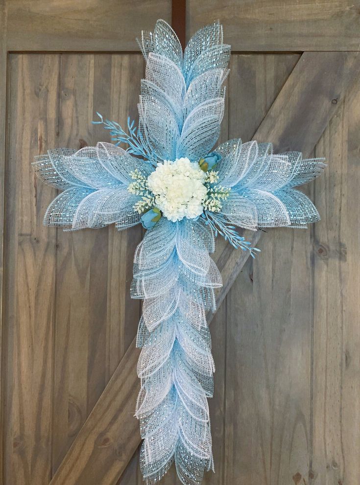 a blue cross decorated with white flowers and feathers