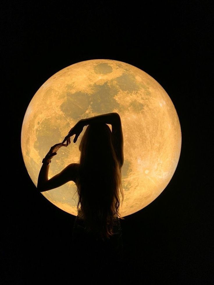 a woman standing in front of a full moon with her hands on her hips and arms behind her head