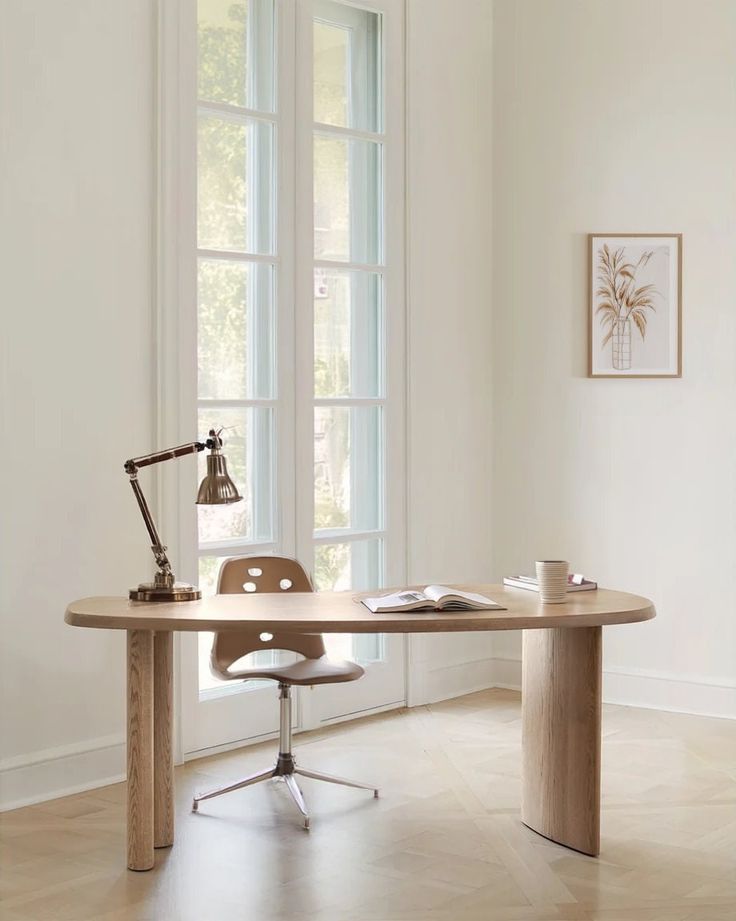 an office desk with a lamp on it in front of two windows and a chair