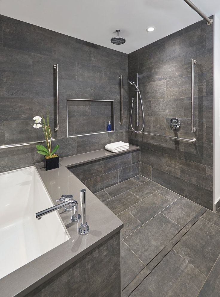 a modern bathroom with gray tile walls and flooring, including a large bathtub