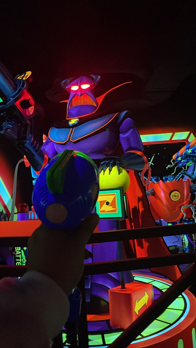 a person holding a toy in front of a neon lit room with an alien figure