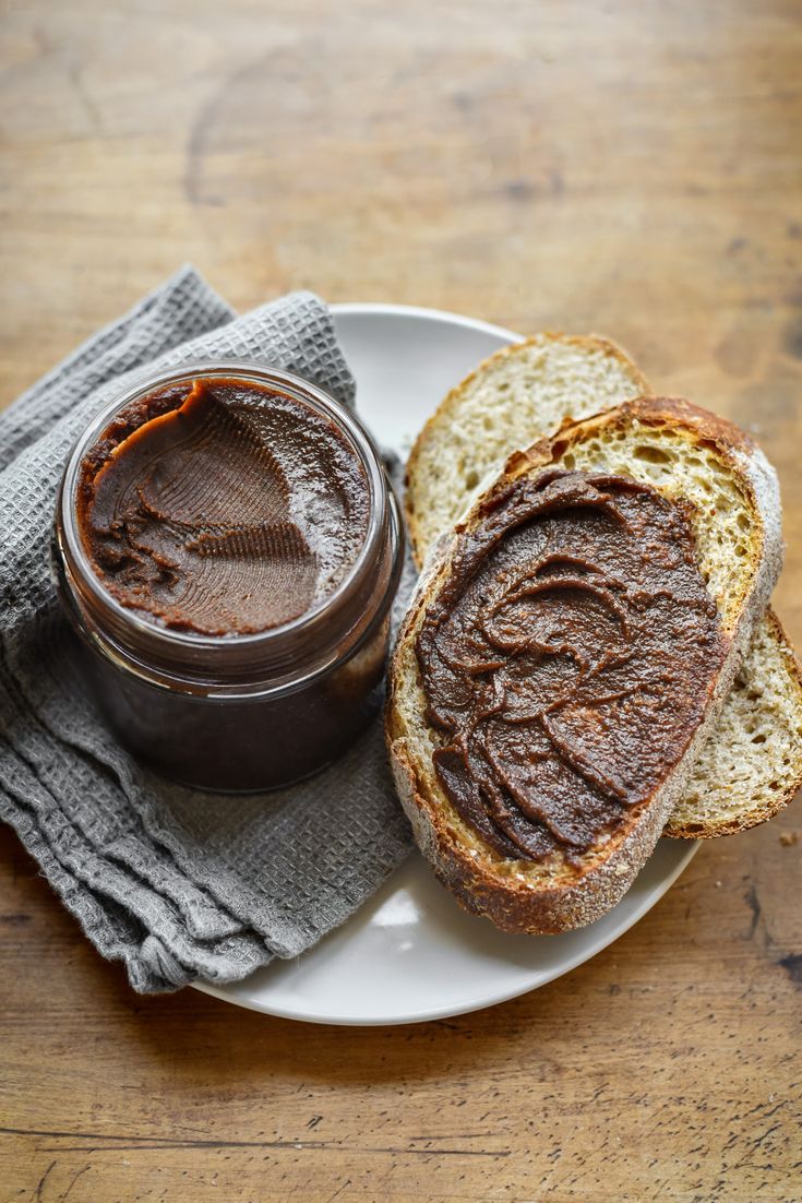 two pieces of bread on a white plate with a jar of peanut butter next to it