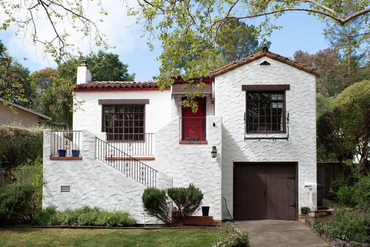 a white house with a red door and stairs leading up to the second story window