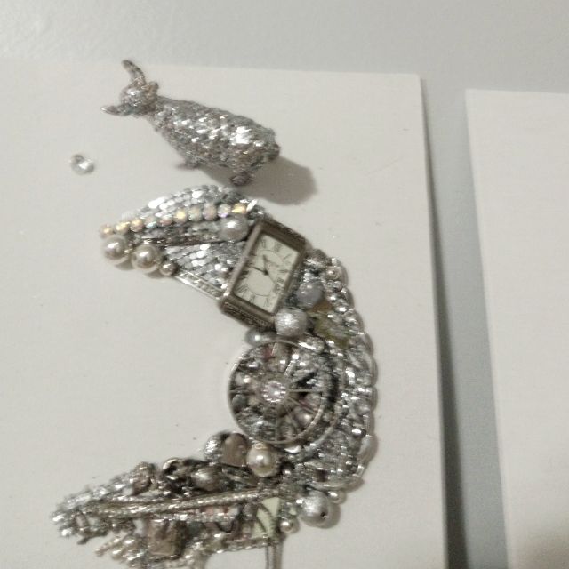 a close up of a clock on a card with pearls and jewels attached to it