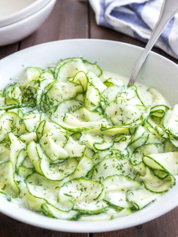 a white bowl filled with cucumber and herbs