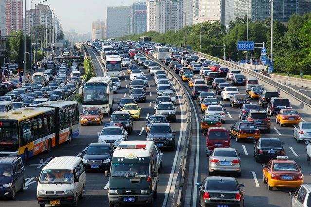 a busy highway filled with lots of cars and buses driving down the middle of it