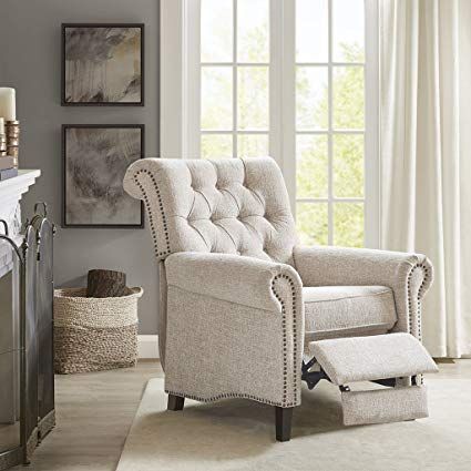 a living room scene with focus on the chair and footstool near the fireplace