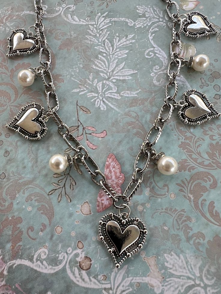 Chain: * silver, electroplated, textured * lead and nickel free * total length 26 inches Charms: * artisan style heart charms with beaded borders * faux pearl and rhinestone Findings: * stainless steel lobster clasp Care Instructions: * avoid showering, swimming or sleeping in jewelry * do not wear jewelry during exercise * apply hairsprays, perfumes or lotions before adding jewelry  🌷YOUR JEWELRY WILL ARRIVE IN A DRAWSTRING BAG. TO LENGTHEN THE LIFE AND BEAUTY OF YOUR JEWELRY, STORE IT IN THE Silver Heart-shaped Jewelry With Pearl Charm, Heart-shaped Silver Necklace With Pearl Charm, Heart Shaped Silver Alloy Charm Necklace, Silver Heart Necklace With Pearl Chain, Heart Shaped Silver Jewelry With Pearl Chain, Silver Heart Necklace With Pearl Chain For Valentine's Day, Silver Pearl Chain Necklace For Valentine's Day, Silver Necklace With Pearl Chain For Valentine's Day, Valentine's Day Silver Jewelry With Pearl Chain