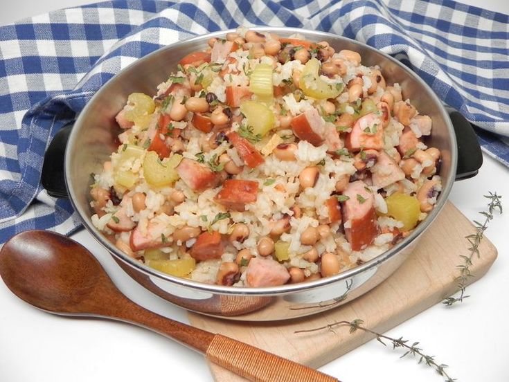 a bowl filled with rice and beans next to a wooden spoon