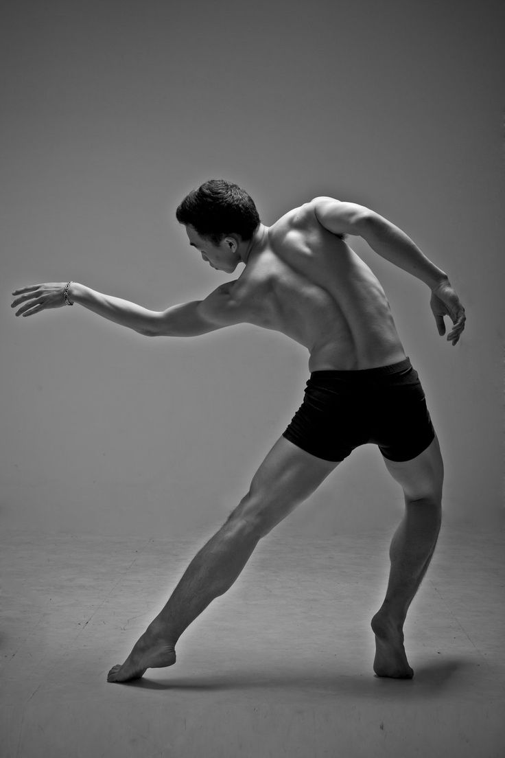 a shirtless man in black and white poses for the camera while holding his arm out