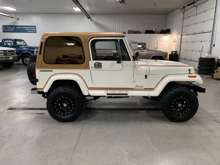 a tan and white jeep parked in a garage