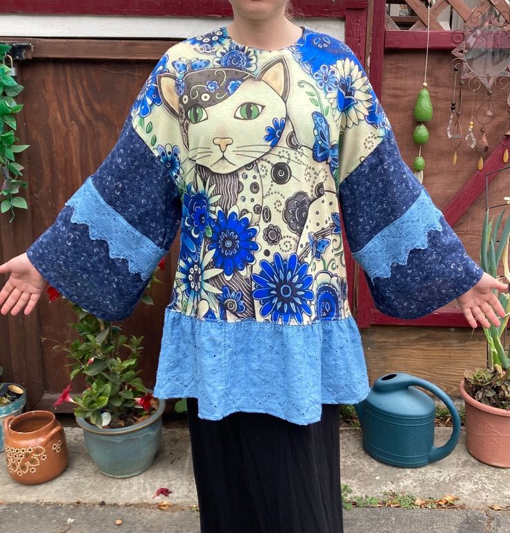 "UPCYCLED with multiple fabrics. OOAK.  The main blouse is stretchy and feels like cotton or cotton blend. The sleeves and ruffle are cotton. All prewashed. Best fits large or XL, but SEE MEASUREMENTS BELOW.   Sleeve length from center back 28\" Bust 46\" Hips 46\" at top of ruffle Length from center back 30\" Model is size Medium My home is smoke free. Clothing is measured while laying flat and unstretched. I highly recommend taking the time to measure something that fits you well for comparison. Remember that you need breathing room that is not included in the measurements.  Any flaws are described above.  All items are sent with delivery confirmation and insurance in the U.S., or First Class International. 30% of the profits for 2023 will go to the following charities : 20% Mercy for An Blue Stretch Tops With Patchwork, Blue Stretch Patchwork Tops, Stretch Long Sleeve Patchwork Tops, Stretch Patchwork Long Sleeve Tops, Lagenlook Patchwork Top With Relaxed Fit, Lagenlook Relaxed Fit Patchwork Tops, Stretch Cotton Tops With Ruffles, Cotton Ruffled Stretch Top, Blue Cotton Patchwork Tops