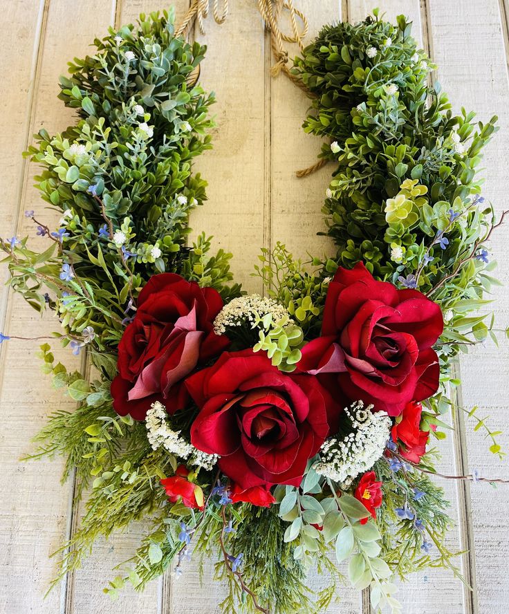 a wreath with red roses and greenery