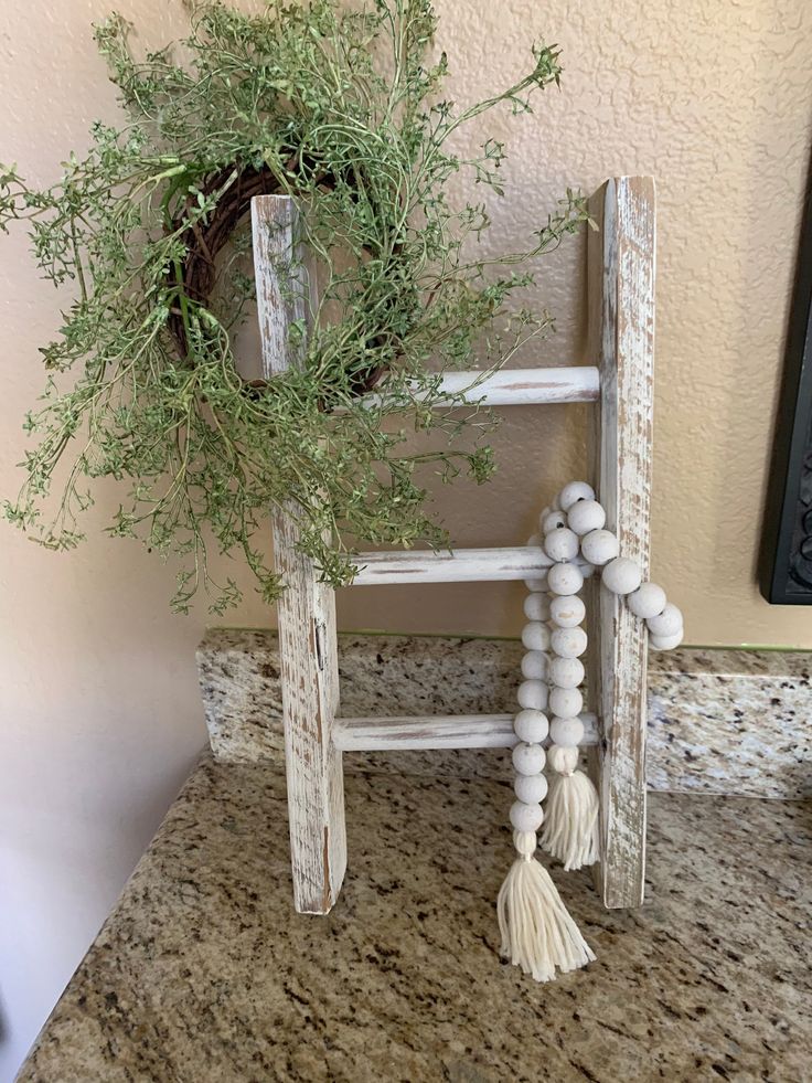 an old ladder is decorated with greenery and beads