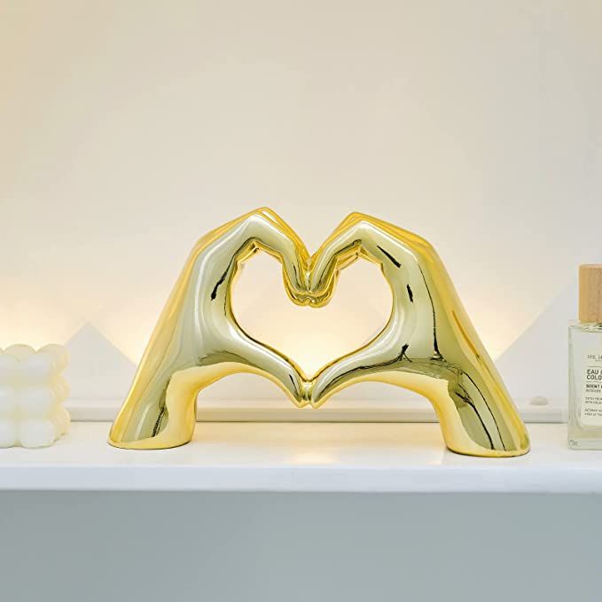 a gold heart shaped object sitting on top of a white shelf next to a bottle