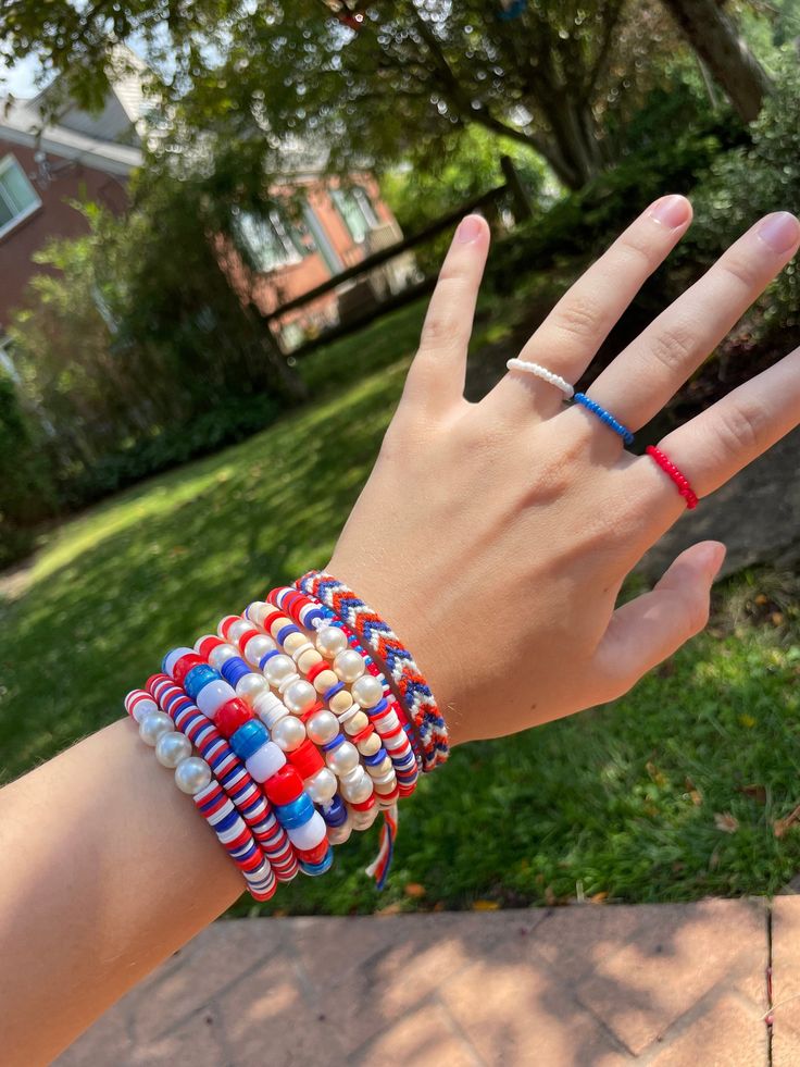 a person's hand with two bracelets on it in front of a house