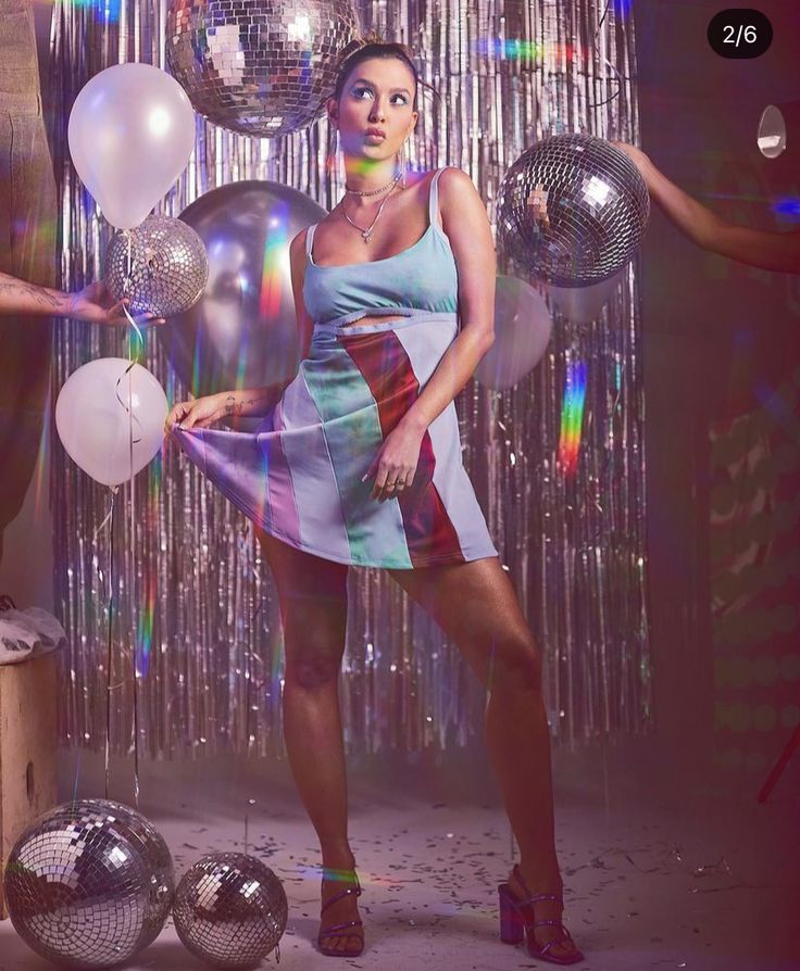 a woman standing in front of balloons and disco balls