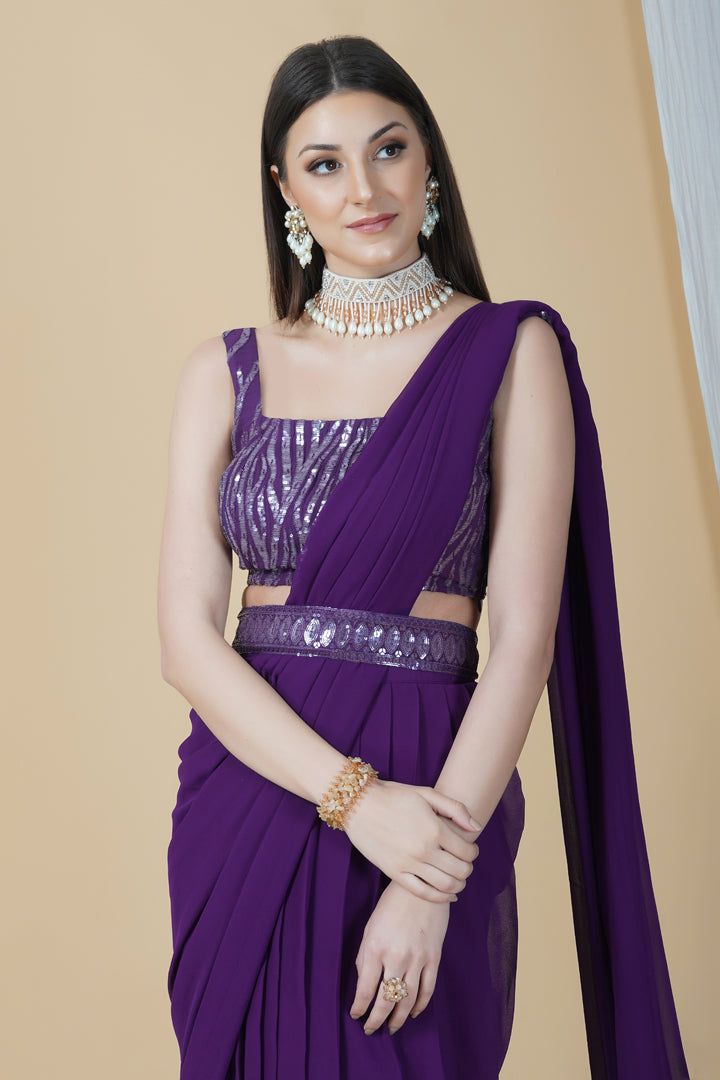 Get ready to leave everyone awestruck with your grace by adorning this ready to wear saree in a dreamy purple hue. With a belt running across and a tie-knot at back, this saree can be perfectly worn for an engagement or a cocktail party.Style Ready to Wear Saree with an embellished belt Dreamy Purple hue Sequins blouse Georgette fabric Specifications Model height - 5'9" Model wearing - S Elegant Purple Pre-draped Saree, Purple Embellished Pre-draped Saree, Embellished Purple Pre-draped Saree, Purple Embellished Georgette Pre-draped Saree, Purple Georgette Pre-draped Saree For Evening, Purple Floor-length Pre-draped Saree For Reception, Purple Bollywood Party Pre-draped Saree, Traditional Purple Pre-draped Saree For Party, Purple Floor-length Evening Lehenga