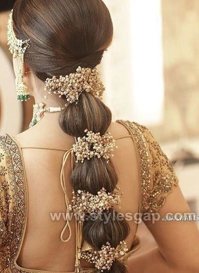 a woman with long hair in a braid and some beads on her head, wearing a gold dress