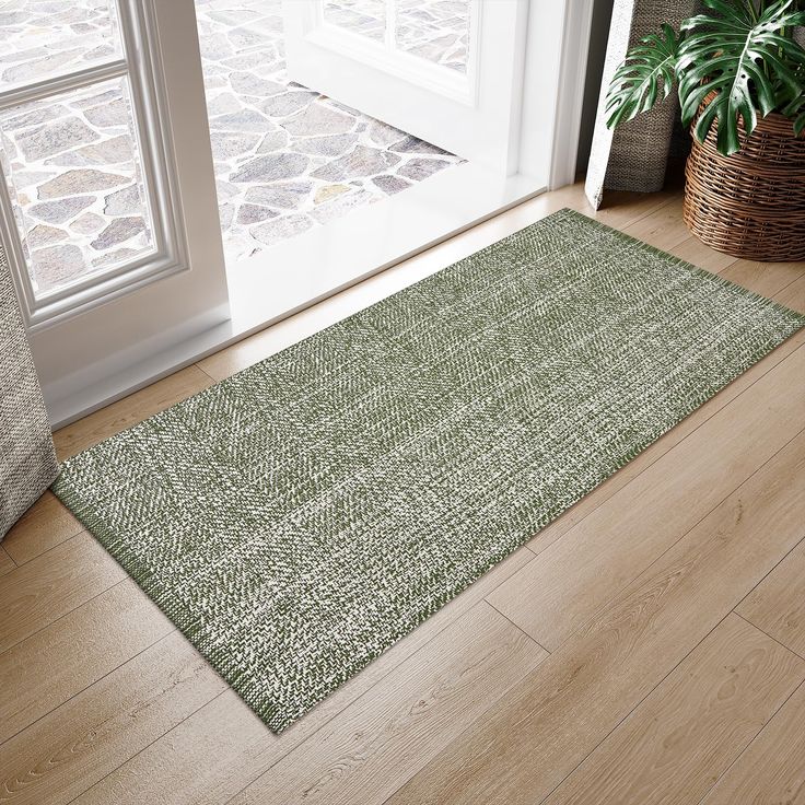 a green rug sitting on top of a hard wood floor next to a door way