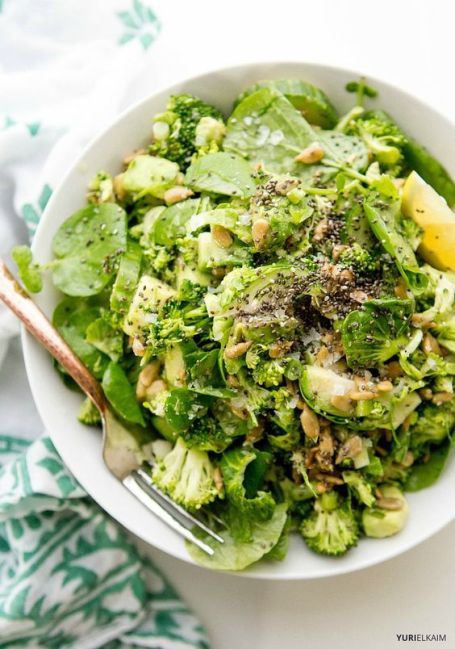 a white bowl filled with broccoli salad and topped with lemon wedged parsley