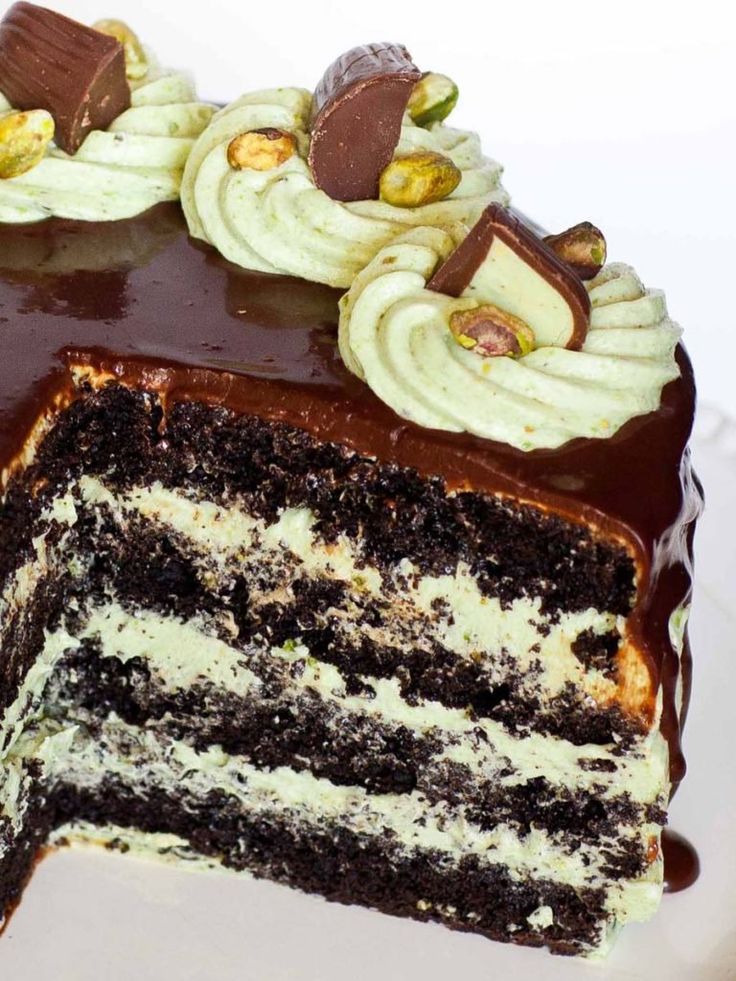 there is a chocolate cake with white frosting and nuts on the top it has one slice cut out