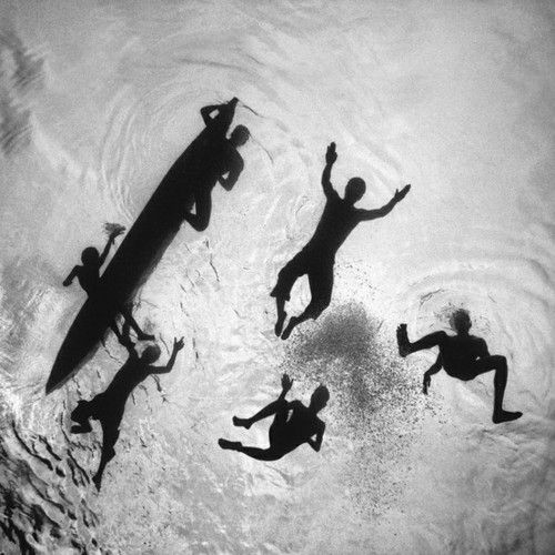 four people are swimming in the water with their surfboards