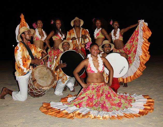 a group of men and women dressed in colorful costumes posing for a photo on the beach