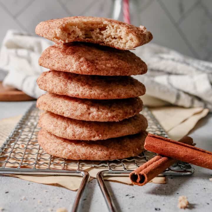 a stack of cookies sitting on top of a cooling rack next to cinnamon sticks and spices