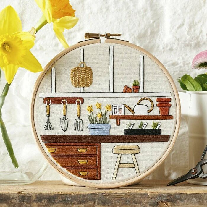 a cross stitch pattern with flowers and gardening tools on the counter in front of a potted plant