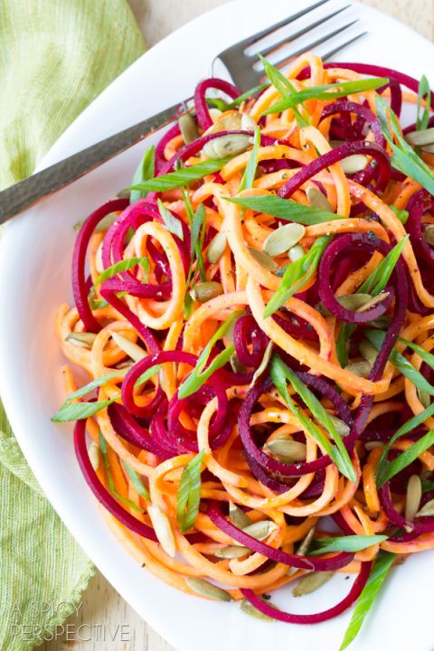 a white plate topped with carrots, onions and sprouts next to a fork