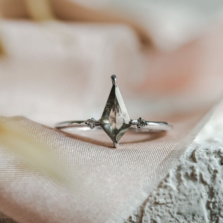 a diamond ring sitting on top of a piece of cloth in front of a bed