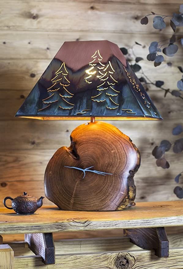 a wooden table with a lamp on top of it next to a teapot and tree stump