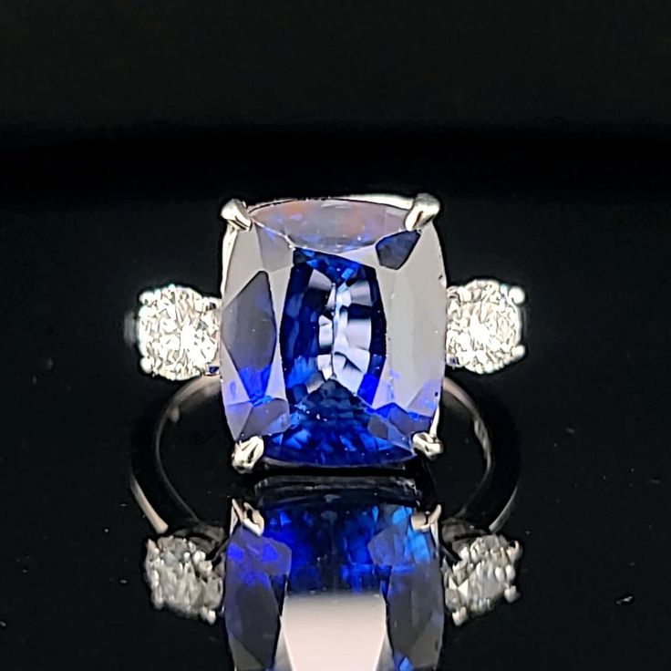 This vintage platinum three-stone ring features a stunning cushion-shaped lab-grown blue sapphire as its center stone, with two lab-grown diamonds on either side. The ring is perfect for special occasions like engagements, weddings, anniversaries, birthdays, Valentine's Day, Christmas, Mother's Day, or graduation, with adjustable sizing to fit a size 7.5 finger. GORGEOUS vintage platinum  engagement three stones ring gem lab-grown blue sapphire in a cushion shape,  Center set gorgeous blue sapph Luxury Cushion Cut Sapphire Ring With Vvs Clarity, Sapphire Platinum Diamond Ring Cushion Cut, Sapphire Cushion Cut Diamond Ring In Platinum, Platinum Sapphire Cushion Cut Diamond Ring, Formal Fine Jewelry Sapphire Cushion Cut Ring, Formal Cushion Cut Sapphire Ring, Formal Sapphire Ring With Cushion Diamond Cut, Formal Sapphire Ring With Cushion Cut, Elegant Sapphire Ring With Vvs Clarity Cushion Cut