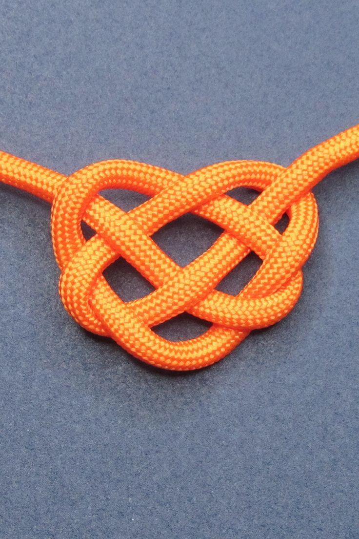 an orange knot on a blue surface with a white cord in the middle and one knot at the end