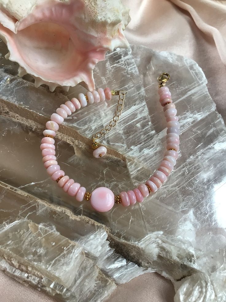 "This pastel pink stone and shell bracelet has gold filled findings. It is a resort beach style. Its length is 7\" with a 1 1/4\" extender chain. The pink Opal rondel  beads and coin conch shell bead are shades of pink and off white. It has a lobster claw clasp" Pink Natural Stones Jewelry For Beach, Adjustable Pink Shell Jewelry, Pink Adjustable Shell Jewelry, Resort Beach, Rose Pastel, Shell Bracelet, Conch Shell, Pink Gemstones, Resort Style