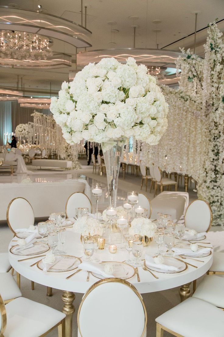 a table set with white flowers and candles for a wedding reception at the ritz