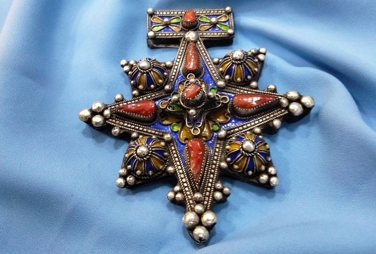 Morocco - Beautiful late 20th century South Moroccan cross called Boghdad in sterling silver, enameled in blue, green and yellow and inlaid with real coral cabochon beads. mainly carried by Sahrawi/Tuareg populations. Fine graining and wonderful silver patina. ✓ Height: 10.5cm. ✓ Width: 9.5 cm. ✓ Leather cord: 54 cm. ✓ Material: sterling silver. ✓ Weight: 76.6 grams. ✓ Origin: South of Morocco 1950s. ✓ Shipping will always be via DHL for free. ✓ Shipping to USA 3-7 business days. ✓ Shipping to E Traditional Collectible Necklace For Festivals, Traditional Cross Pendant Necklace As Gift, Traditional Cross Pendant Necklace For Gift, Antique Cross Necklaces For Collectibles, Traditional Cross Pendant Necklace With Intricate Design, Traditional Necklace With Intricate Cross Pendant, Antique Collectible Cross Jewelry, Handmade Cross Jewelry Collectible, Traditional Blue Jewelry With Large Pendant