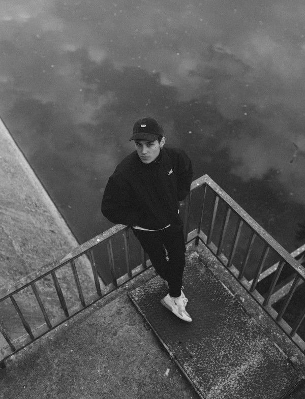 black and white photograph of a man standing on the edge of a railing near water